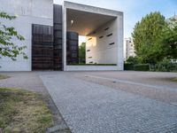 a building with concrete and glass, an entrance in the background and a bench with a wooden seat sitting in front