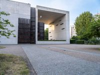 a building with concrete and glass, an entrance in the background and a bench with a wooden seat sitting in front