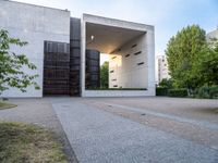 a building with concrete and glass, an entrance in the background and a bench with a wooden seat sitting in front