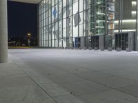 a night time scene at an office building outside of a lobby, including glass windows and a red fire hydrant