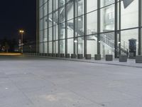 a night time scene at an office building outside of a lobby, including glass windows and a red fire hydrant