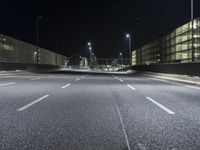 the roadway of an urban street is empty at night time as street lights shine brightly