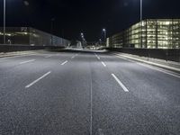 the roadway of an urban street is empty at night time as street lights shine brightly