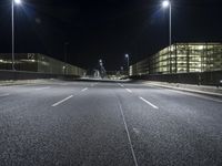 the roadway of an urban street is empty at night time as street lights shine brightly