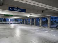 there is an empty parking garage with a sign in the ceiling above it and on the right corner, a bright light shines in the ground