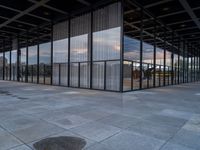 an empty building with large panes of glass reflecting in the puddles of concrete