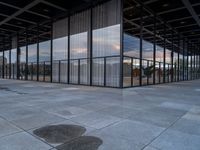 an empty building with large panes of glass reflecting in the puddles of concrete