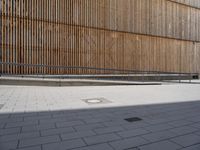 skateboarders in front of a modern building with large wood screens on the outside of it