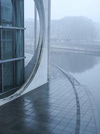 a building with a circle window overlooking some water in the fog while onlookers are talking