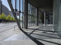 the building has glass walls that reflect light on its outside windows and make shadows on the street