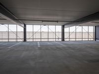 a empty parking garage filled with lots of windows and lots of empty concrete flooring
