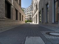 a narrow cobbled street between two buildings, with one person in a wheelchair walking down the middle