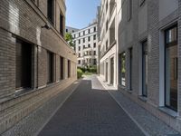 a narrow cobbled street between two buildings, with one person in a wheelchair walking down the middle