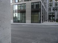 a woman in red top standing on the corner of an empty street next to tall buildings