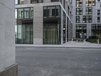 a woman in red top standing on the corner of an empty street next to tall buildings