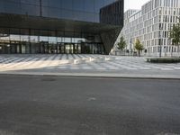 large glass building with benches near a street corner on a sunny day from outside the area