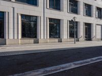 a sidewalk with a bench and brick sidewalk and building with a sky background and reflection on water