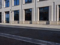 a sidewalk with a bench and brick sidewalk and building with a sky background and reflection on water