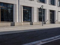 a sidewalk with a bench and brick sidewalk and building with a sky background and reflection on water