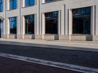 a sidewalk with a bench and brick sidewalk and building with a sky background and reflection on water