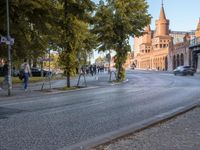 a street that has some people walking and bicycles in the road underneath a bridge on a brick road