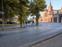 a street that has some people walking and bicycles in the road underneath a bridge on a brick road