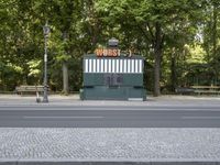 an empty street with benches sitting on top of it by the side walk next to trees