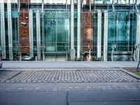 a person walks by a large metal pole near an open brick and glass building with glass walls