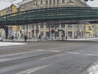 two people walking on the road by an overpass in the winter time, during a heavy snow storm