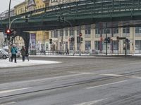 two people walking on the road by an overpass in the winter time, during a heavy snow storm