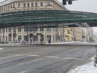 two people walking on the road by an overpass in the winter time, during a heavy snow storm