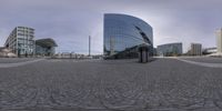 the street is cobbled and empty in front of large buildings and glass windows is an illusion