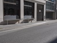 a street corner near some large buildings with a bench in the middle of it on the sidewalk