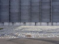 a fire hydrant is on the cement side of a building with steel grates