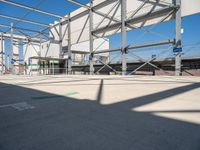 a metal structure with lots of columns and green signs on it in the sun near some buildings