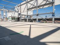 a metal structure with lots of columns and green signs on it in the sun near some buildings