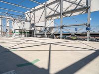 a metal structure with lots of columns and green signs on it in the sun near some buildings