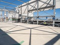 a metal structure with lots of columns and green signs on it in the sun near some buildings