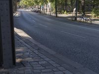 a small brick road is shown lined with trees and brick sidewalks on either side of the street