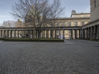 the courtyard at the end of a building in the winter with pillars and columns leading up to it