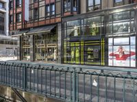 a bridge over a road in front of a store with lots of windows and large glass windows