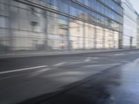 a large building is reflected in the side of the street that goes along this narrow road