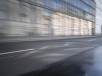 a large building is reflected in the side of the street that goes along this narrow road