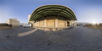 a fisheye lens picture of an outside of a building and bus station with the roof up