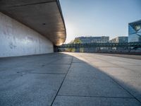 a skateboarder riding on a cement ramp next to a city street under a bridge