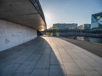 a skateboarder riding on a cement ramp next to a city street under a bridge