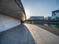 a skateboarder riding on a cement ramp next to a city street under a bridge