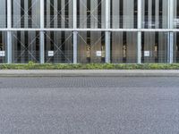 a tall building with many windows and grass on the curb next to the road,