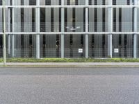 a tall building with many windows and grass on the curb next to the road,