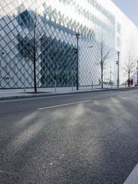 an image of a city street in the sun by a building and fenced in